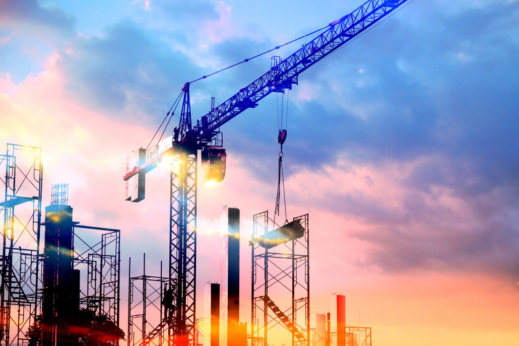 tower cranes at construction site with sun