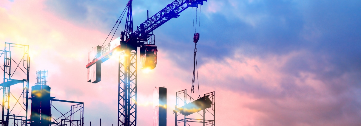 tower cranes at construction site with sun
