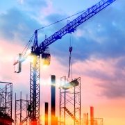 tower cranes at construction site with sun