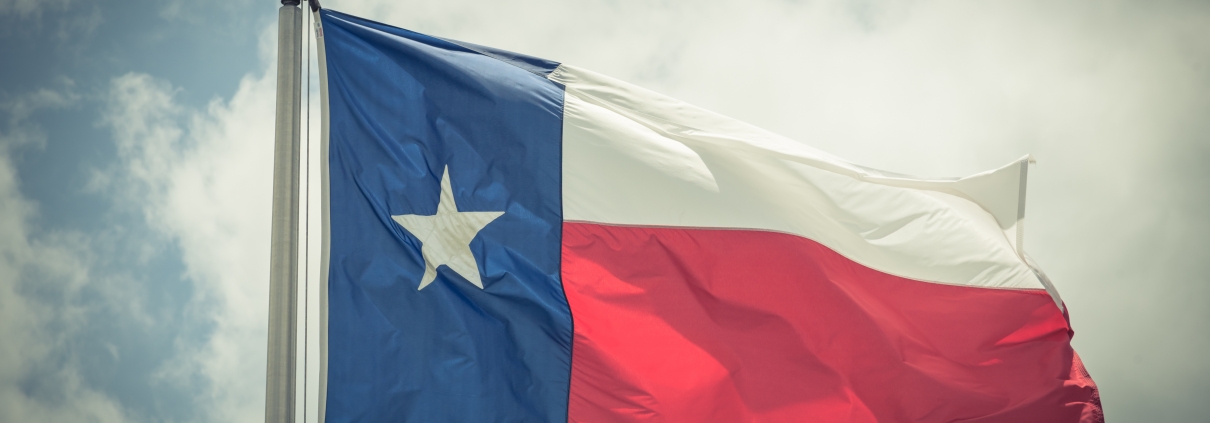 Large Texas (The Lone Star) flag waving on flag pole with cloud blue sky. Windy and sunny day with waving flag blowing/flowing. Ruffled Texas flag. Room for text, copy space. Vintage tone.